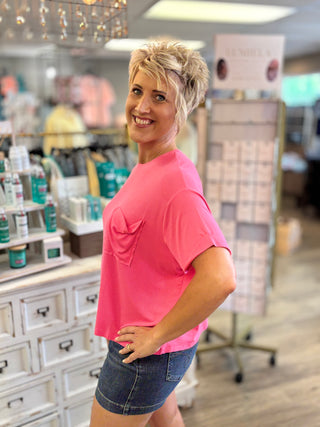 Woman in a pink shirt and denim shorts standing in a store setting.