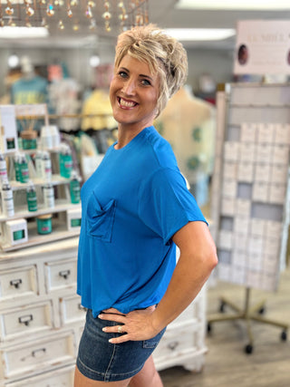 Woman wearing a blue top and denim shorts in a store setting