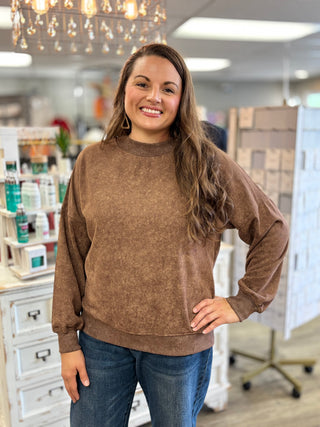 Model wearing a brown mock neck long sleeve top with jeans