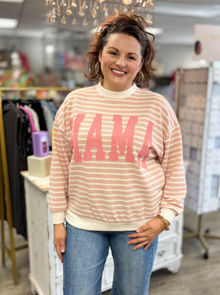 Woman wearing a striped sweater with 'MAMA' printed on it in a store setting.