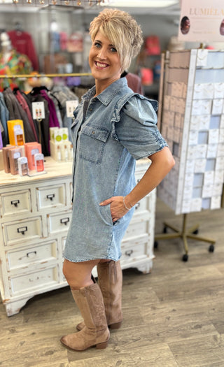 Woman wearing a denim dress and brown knee-high boots in a store setting.