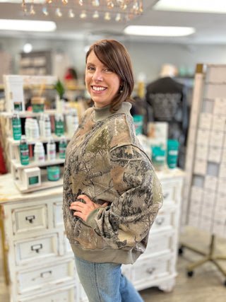 Model wearing a camo printed mock neck sweatshirt and denim