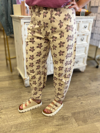 Model wearing cream colored floral printed barrel style pants