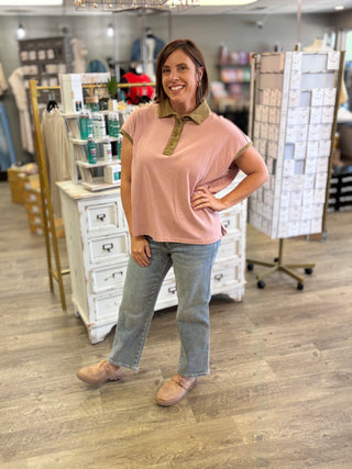 Model wearing an oversized top in sugar magnolia color with brown trim, button detail, and light wash denim