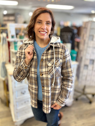 Model wearing a brown, cream, and blue plaid shacket with jeans
