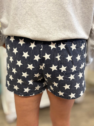 Navy shorts with white star pattern worn by a person, blurred background