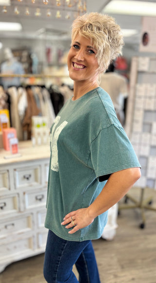 Woman wearing a green t-shirt with a graphic design in a store setting