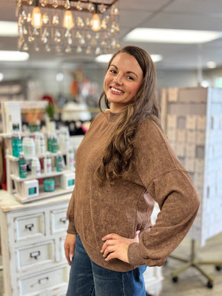 Model wearing a brown mock neck long sleeve top with jeans