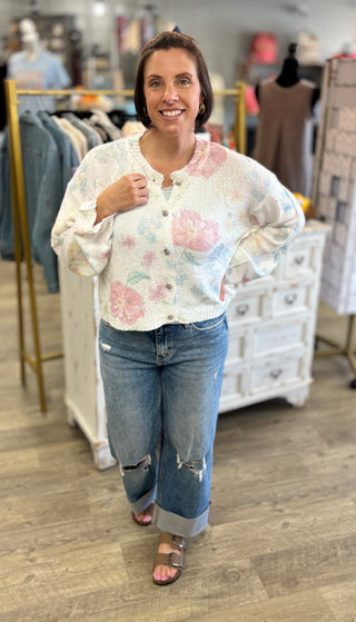 Woman wearing a floral cardigan and jeans in a store setting