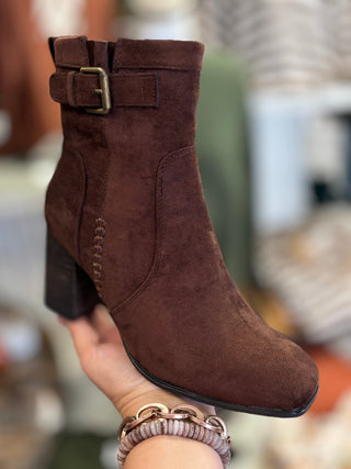A brown bootie with buckle and exposed stitching detail
