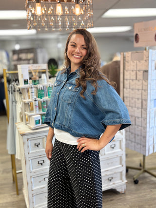 Model wearing medium wash denim jacket with 3/4 sleeves and button detail 