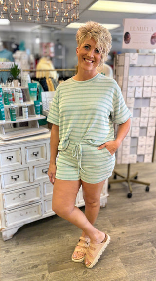 Model wearing green striped shorts set in a store setting