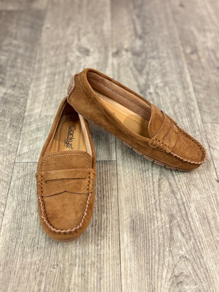 A pair of camel color suede penny loafers resting on a gray wood-look floor. 