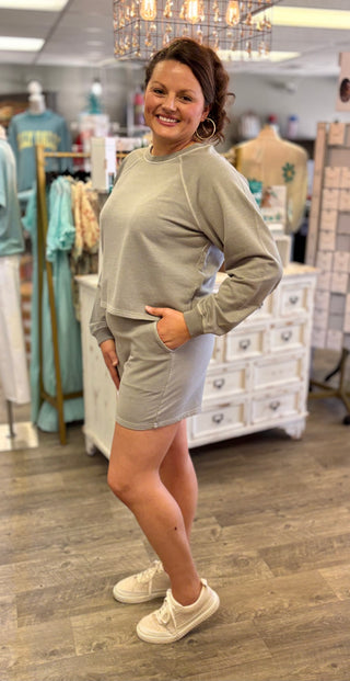 Woman wearing a light gray sweatshirt and shorts in a store setting