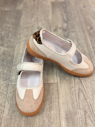 A pair of women's Mary Jane style shoes in off-white and beige suede, featuring a brown and black leopard print accent on the heel, displayed on a gray wood-look floor.