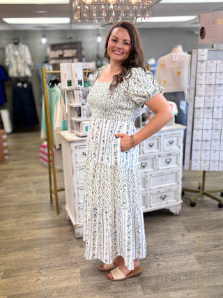 Woman in a floral dress standing in a store with shelves and products in the background