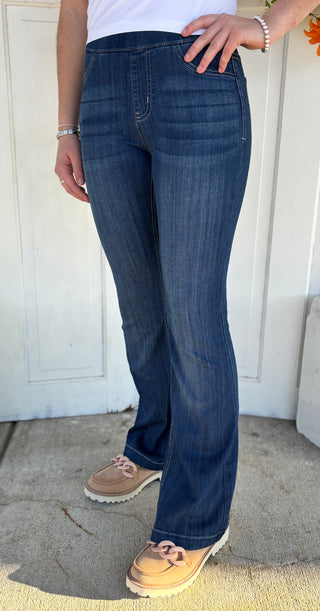Person wearing blue jeans standing against a white door.