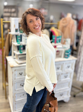 Model wearing a cream colored raised ribbed textured long sleeve top and jeans