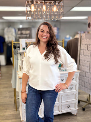 Model wearing white top featuring a v-neckline and 3/4 length sleeves and jeans