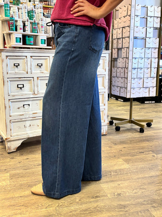 Model wearing dark wash wide leg jeans with drawstring detail