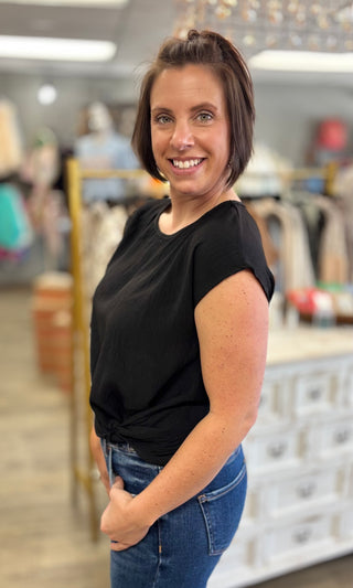 Woman wearing a black top and blue jeans standing in a store setting