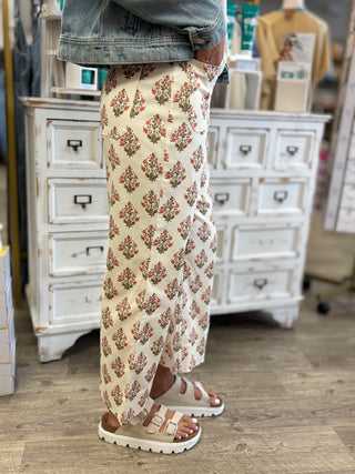Model wearing cream denim bottoms with a rust and green floral pattern