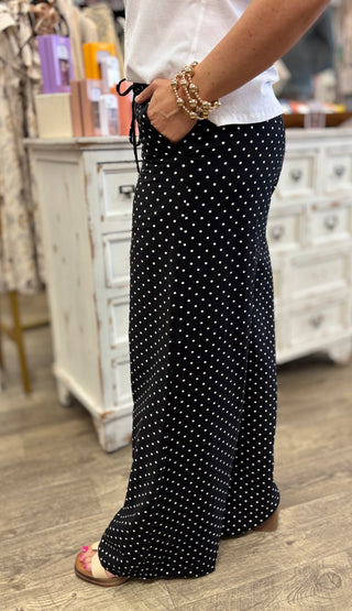 Person wearing black polka dot pants with a blurred indoor background