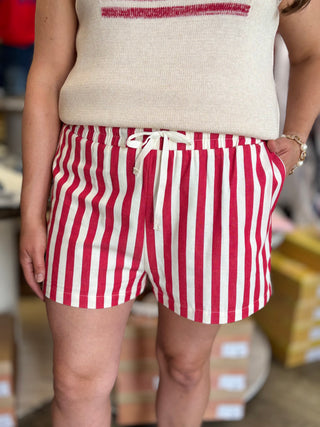 Model wearing red and cream striped shorts with drawstring detail