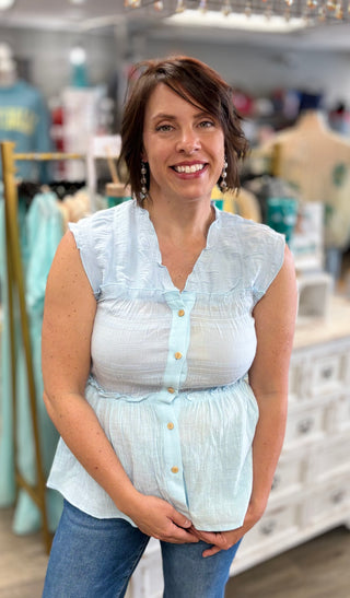 Woman wearing a light blue blouse with white buttons in a store setting