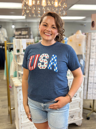 Woman wearing a blue t-shirt with 'USA' design in a store setting
