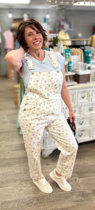 Model wearing cream and blue floral bib overalls