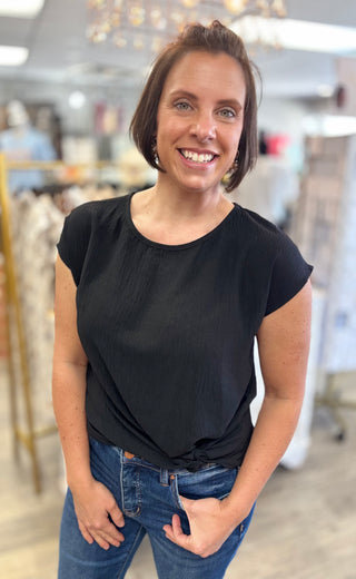 Woman wearing a black top and jeans in a store setting