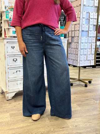 Model wearing dark wash wide leg jeans with drawstring detail