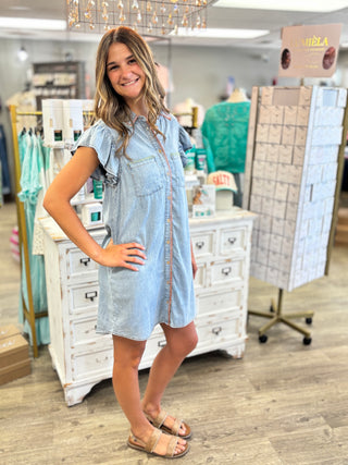 Model wearing chambray dress with green and orange trim stitching detail and button down front 