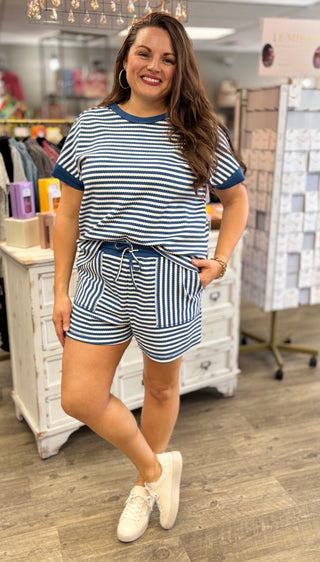 Model wearing a blue and white striped outfit in a store setting