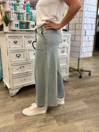 Model wearing faded teal sweat pants with pockets and drawstring detail