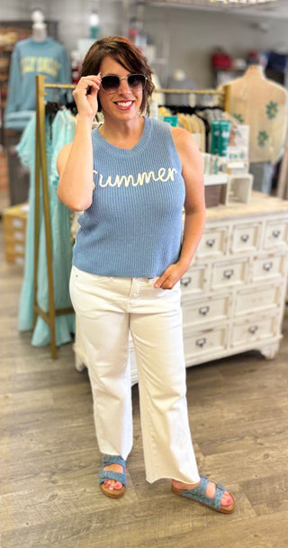 Model wearing blue ‘summer’ sweater vest with white denim 