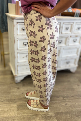 Model wearing cream colored floral printed barrel style pants