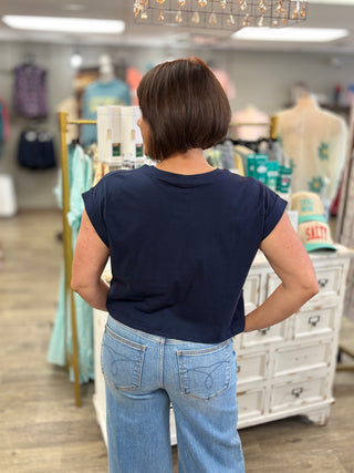 Person wearing a navy blue top and light blue jeans in a store setting