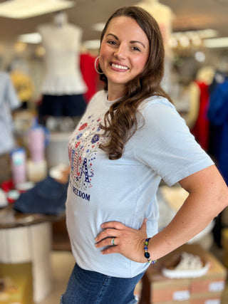 Woman wearing a light blue t-shirt with a graphic design in a store setting