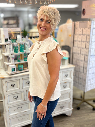 Model wearing beige top with ruffle detail and jeans