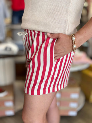 Model wearing red and cream striped shorts with drawstring detail