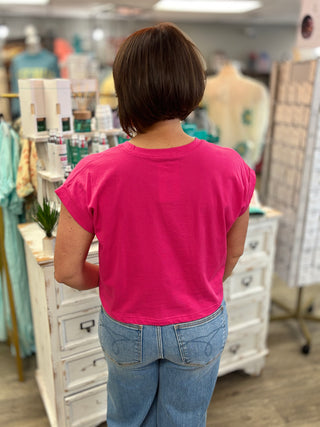 Person wearing a pink shirt and blue jeans standing in a store.
