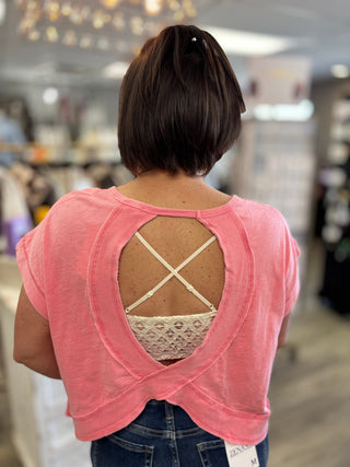 Person wearing a pink top with an open back design in a store setting
