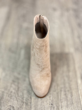 A single beige suede ankle boot shown from a top-down angle on a gray wood-look floor.