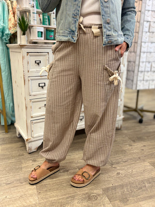 Model wearing taupe and cream striped pants with tie details
