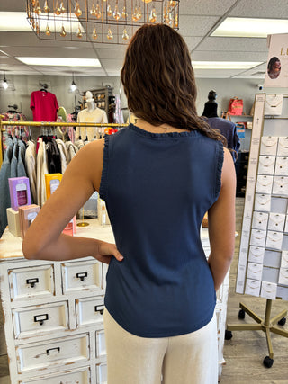 Person in a blue top standing in a store with clothing racks and displays.