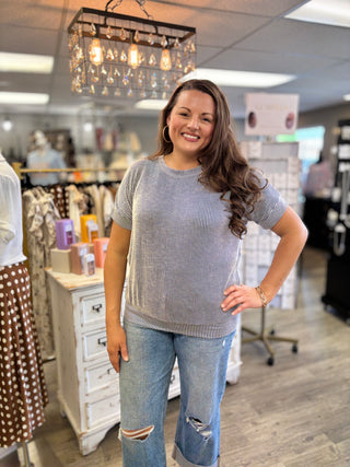 Woman standing in a store wearing a navy and white striped blouse and jeans, smiling.