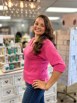 Model wearing hot pink top featuring a v-neckline and 3/4 length sleeves and jeans 