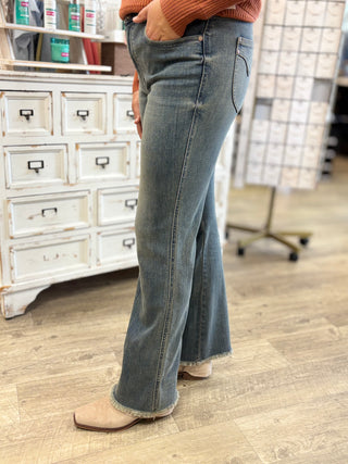 Model wearing Judy Blue bootcut jeans with a frayed hem in a vintage grey wash